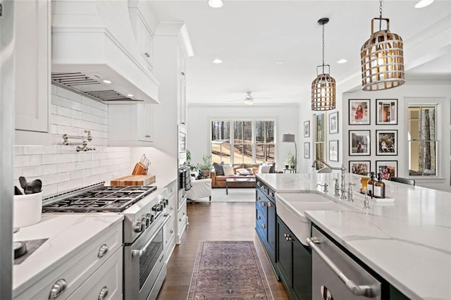 kitchen featuring a ceiling fan, a sink, open floor plan, white cabinets, and appliances with stainless steel finishes
