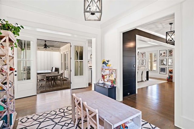 interior space with ceiling fan with notable chandelier, wood finished floors, and ornamental molding