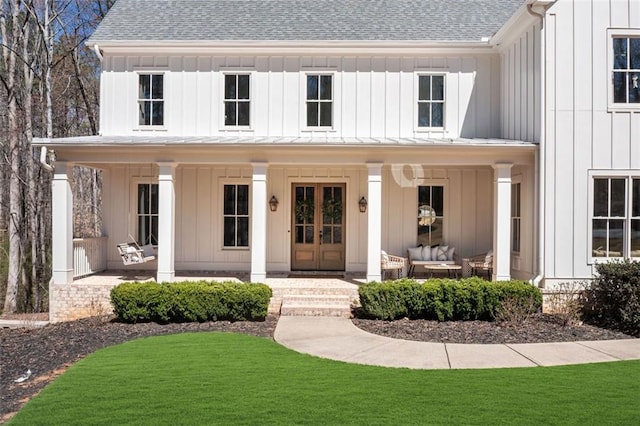 view of front facade with outdoor lounge area, a front yard, board and batten siding, and french doors