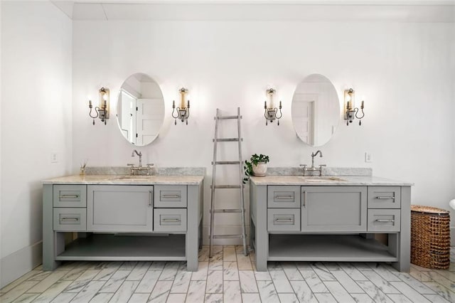 full bath with two vanities, marble finish floor, and a sink