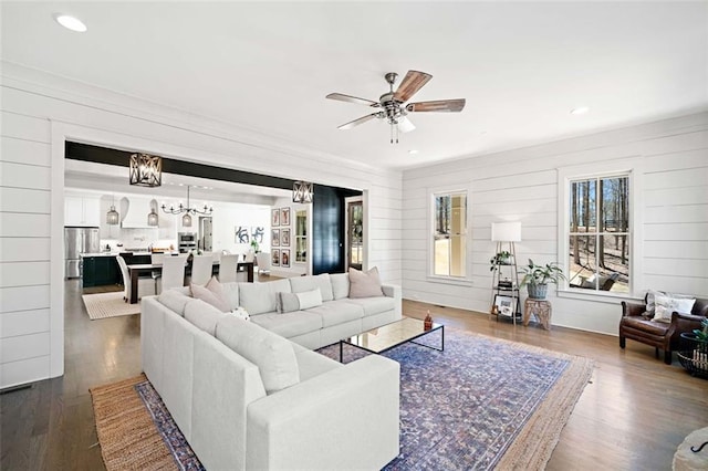 living area with ceiling fan with notable chandelier, recessed lighting, and dark wood-style flooring