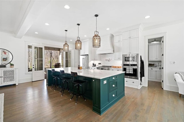 kitchen with white cabinets, stainless steel appliances, premium range hood, green cabinets, and tasteful backsplash