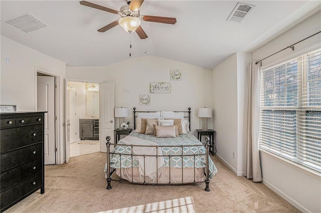 carpeted bedroom featuring lofted ceiling, ensuite bathroom, visible vents, and baseboards