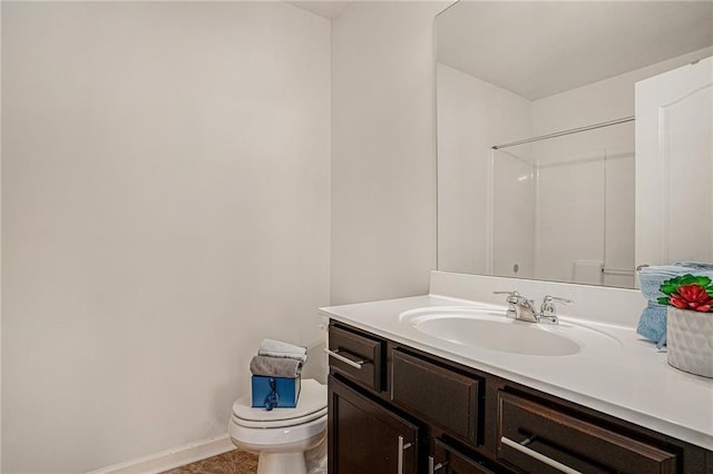 bathroom with toilet, baseboards, a shower, and vanity