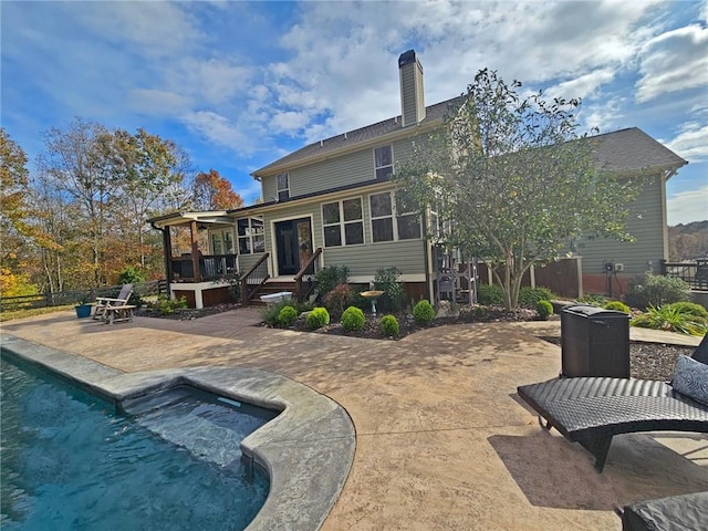 rear view of house with a pool with hot tub and a patio