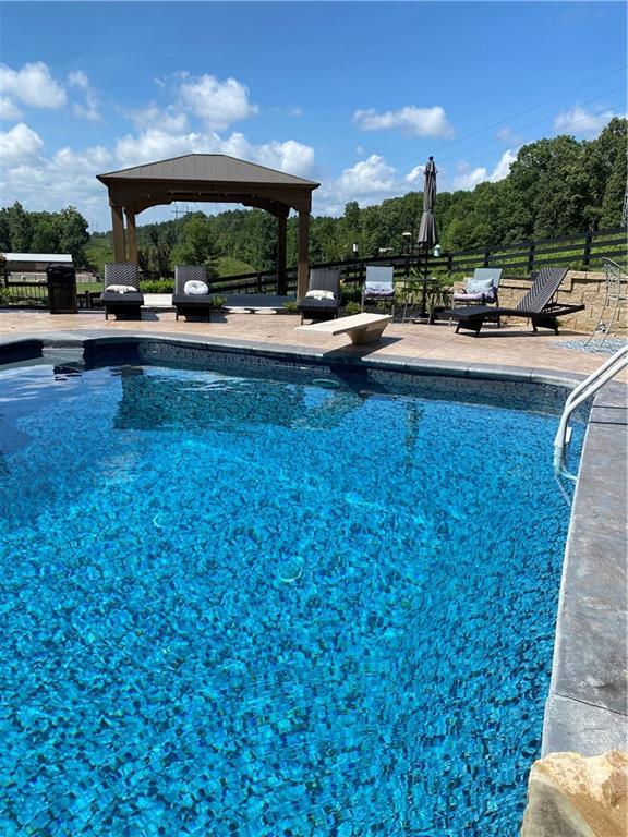 view of pool featuring a gazebo, a diving board, and a patio area