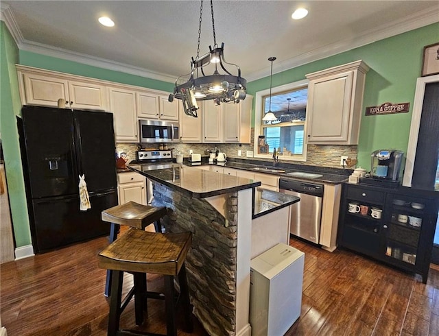 kitchen with appliances with stainless steel finishes, hanging light fixtures, dark hardwood / wood-style floors, a center island, and ornamental molding