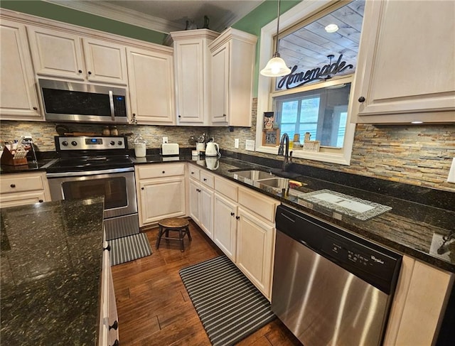 kitchen with appliances with stainless steel finishes, dark hardwood / wood-style floors, pendant lighting, sink, and dark stone countertops