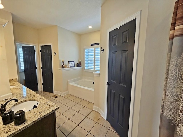 bathroom with a tub to relax in, tile patterned floors, and vanity