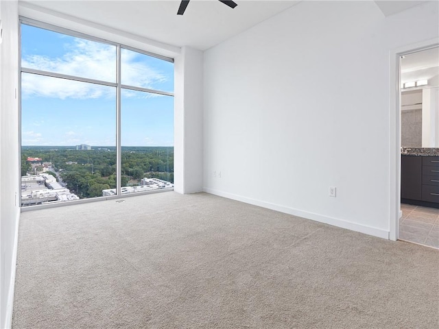 carpeted empty room with floor to ceiling windows and ceiling fan