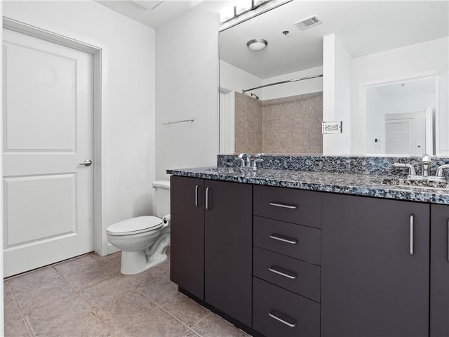 bathroom featuring vanity, toilet, a tile shower, and tile patterned floors