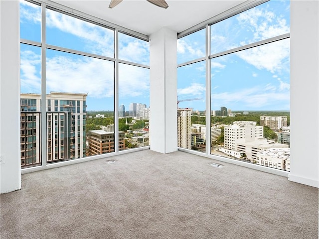 spare room featuring plenty of natural light, carpet, floor to ceiling windows, and ceiling fan