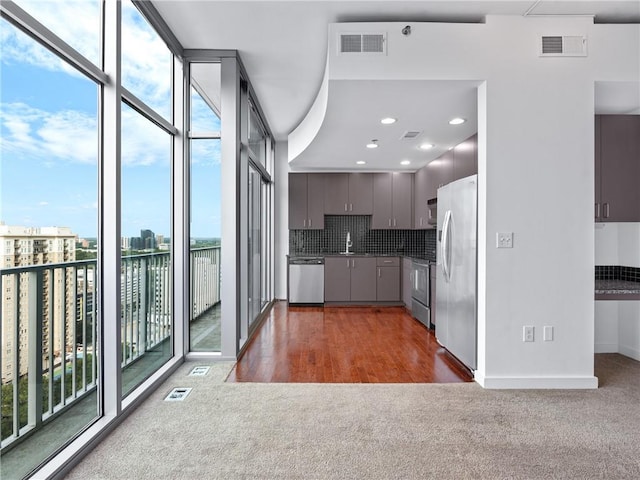 kitchen with backsplash, appliances with stainless steel finishes, dark hardwood / wood-style flooring, sink, and a water view