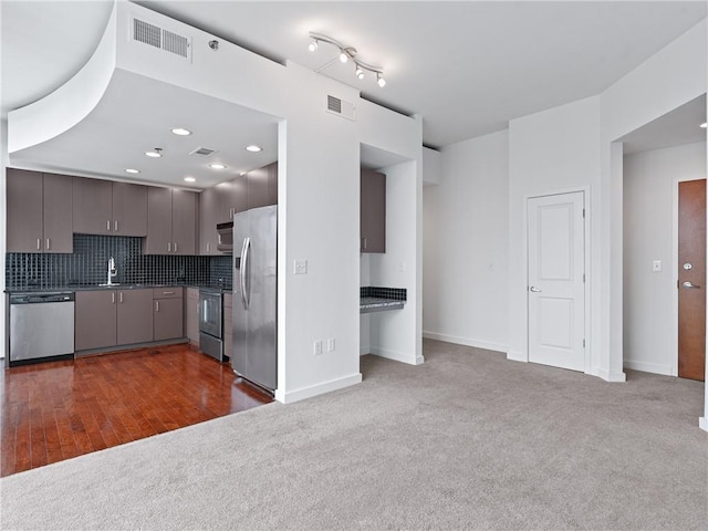 kitchen with appliances with stainless steel finishes, sink, decorative backsplash, and dark hardwood / wood-style floors