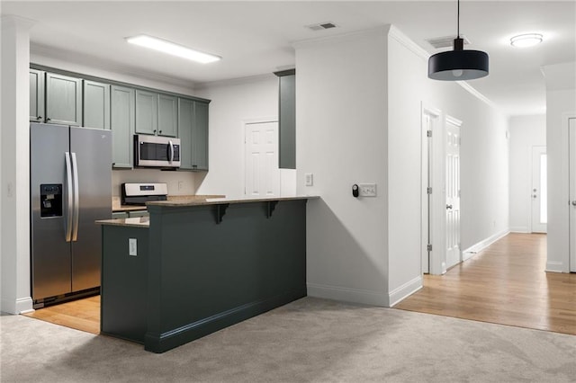 90 Grove Park Ln, Woodstock, GA 30189 - kitchen with appliances with stainless steel finishes, a peninsula, light carpet, crown molding, and hanging light fixtures