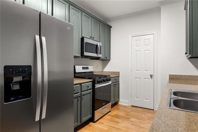 90 Grove Park Ln, Woodstock, GA 30189 - kitchen featuring appliances with stainless steel finishes, crown molding, light wood-style floors, light countertops, and a sink