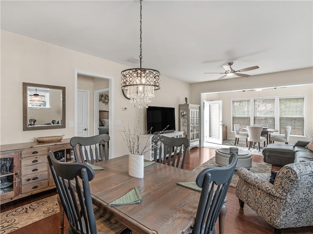 dining area with visible vents, wood finished floors, and ceiling fan with notable chandelier