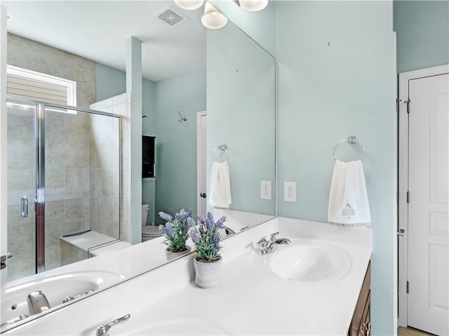 full bathroom featuring visible vents, toilet, a sink, a shower stall, and double vanity