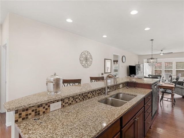 kitchen featuring a sink, open floor plan, pendant lighting, recessed lighting, and dark wood-style flooring