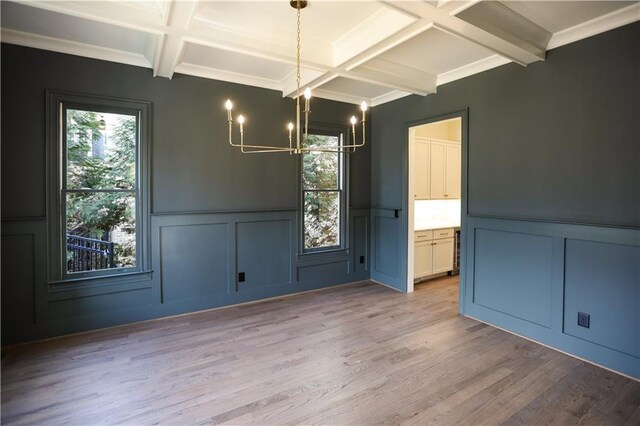 unfurnished dining area featuring beamed ceiling, coffered ceiling, and light wood-type flooring