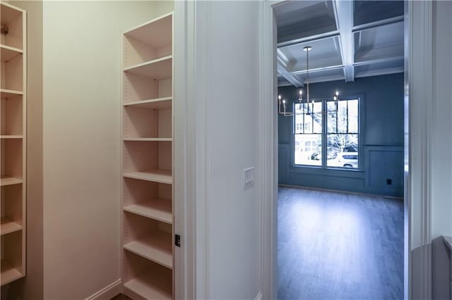 interior space with an inviting chandelier, wood-type flooring, coffered ceiling, and beamed ceiling