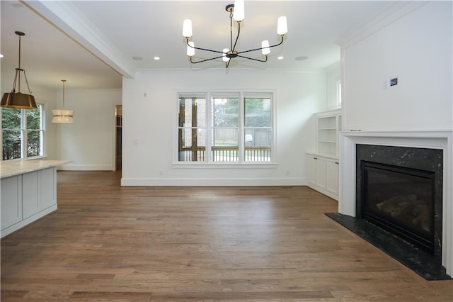 unfurnished living room with a fireplace, a notable chandelier, dark wood-type flooring, and ornamental molding