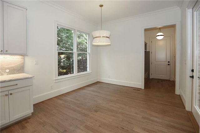 unfurnished dining area with crown molding and wood-type flooring