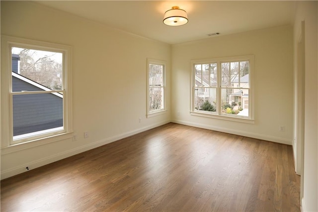 empty room with plenty of natural light and wood-type flooring