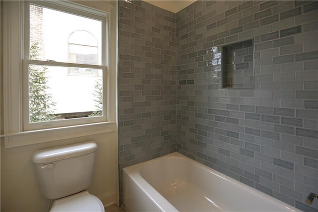 bathroom featuring tiled shower / bath, a healthy amount of sunlight, and toilet