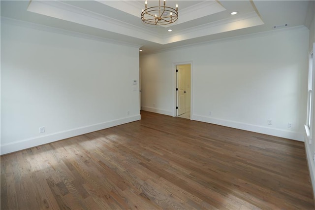 spare room featuring a raised ceiling, ornamental molding, hardwood / wood-style floors, and a notable chandelier