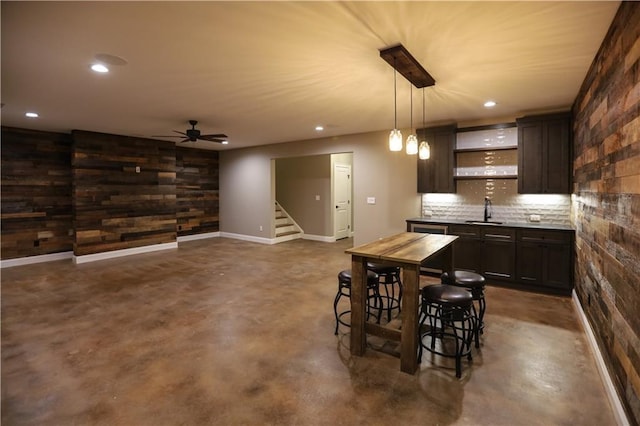 kitchen with pendant lighting, sink, a breakfast bar area, dark brown cabinetry, and decorative backsplash