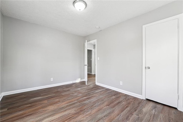 empty room with dark hardwood / wood-style flooring and a textured ceiling