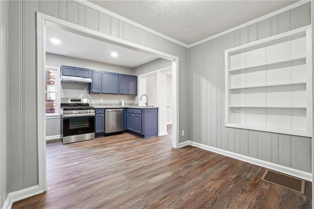 kitchen with dark hardwood / wood-style floors, sink, built in features, appliances with stainless steel finishes, and a textured ceiling