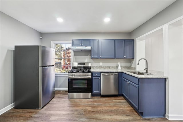 kitchen featuring light stone countertops, stainless steel appliances, sink, dark hardwood / wood-style floors, and blue cabinets