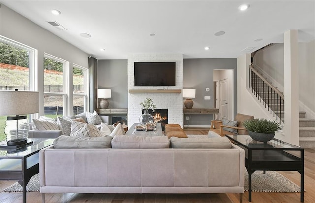 4297 Azalea Ridge Way, Hoschton, GA 30548 - living area featuring wood finished floors, stairway, a brick fireplace, and recessed lighting