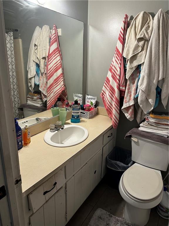 bathroom with tile patterned floors, vanity, toilet, and curtained shower