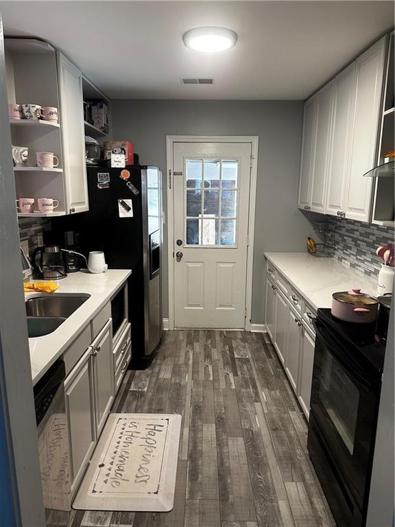 kitchen with dark wood-type flooring, sink, black / electric stove, stainless steel dishwasher, and white cabinets