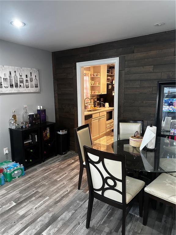 dining room featuring sink, hardwood / wood-style floors, and wood walls