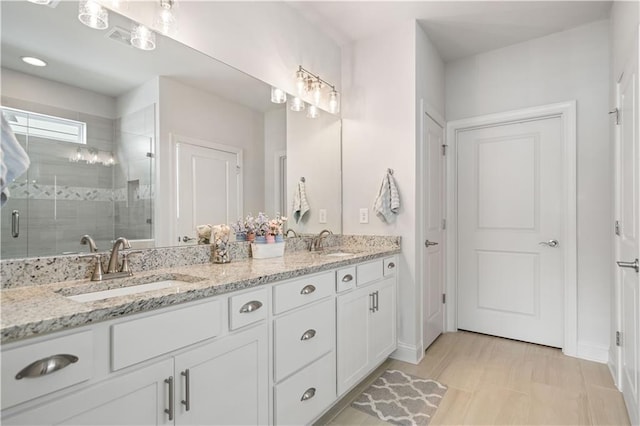 full bath featuring a stall shower, visible vents, a sink, and double vanity