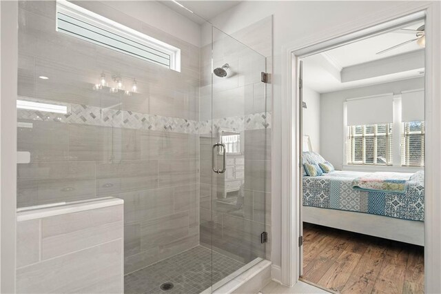 full bath with a healthy amount of sunlight, ensuite bath, wood finished floors, and a shower stall