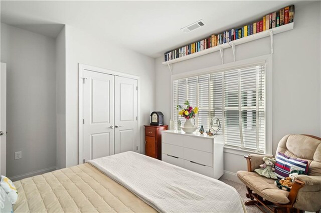 carpeted bedroom featuring baseboards, visible vents, and a closet