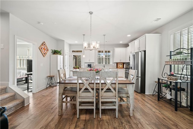 dining room featuring a healthy amount of sunlight, a chandelier, and wood finished floors