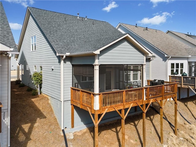 back of property featuring a deck, roof with shingles, and a sunroom