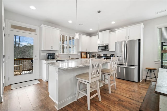 kitchen with tasteful backsplash, dark wood-style floors, a kitchen island, stainless steel appliances, and white cabinetry