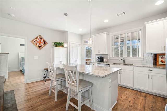 kitchen with light wood-style floors, visible vents, a breakfast bar area, and tasteful backsplash