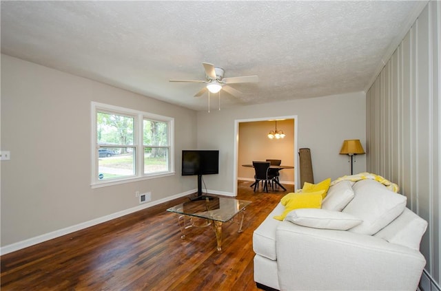 living room featuring a textured ceiling, ceiling fan with notable chandelier, and dark hardwood / wood-style flooring