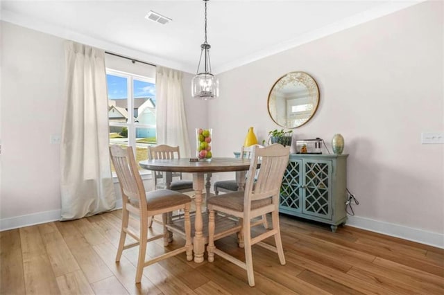 dining room with light wood-type flooring, visible vents, and baseboards