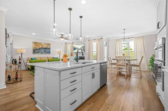 kitchen featuring a sink, open floor plan, ceiling fan, light countertops, and appliances with stainless steel finishes