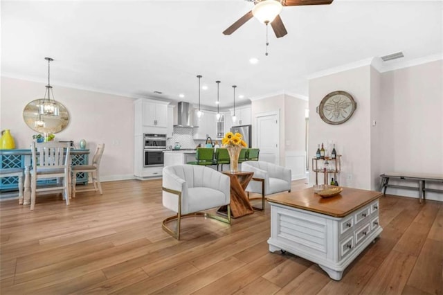 living area featuring crown molding, visible vents, and ceiling fan with notable chandelier