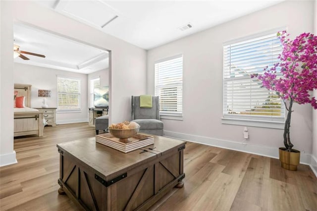 living area featuring light wood-type flooring, visible vents, and baseboards